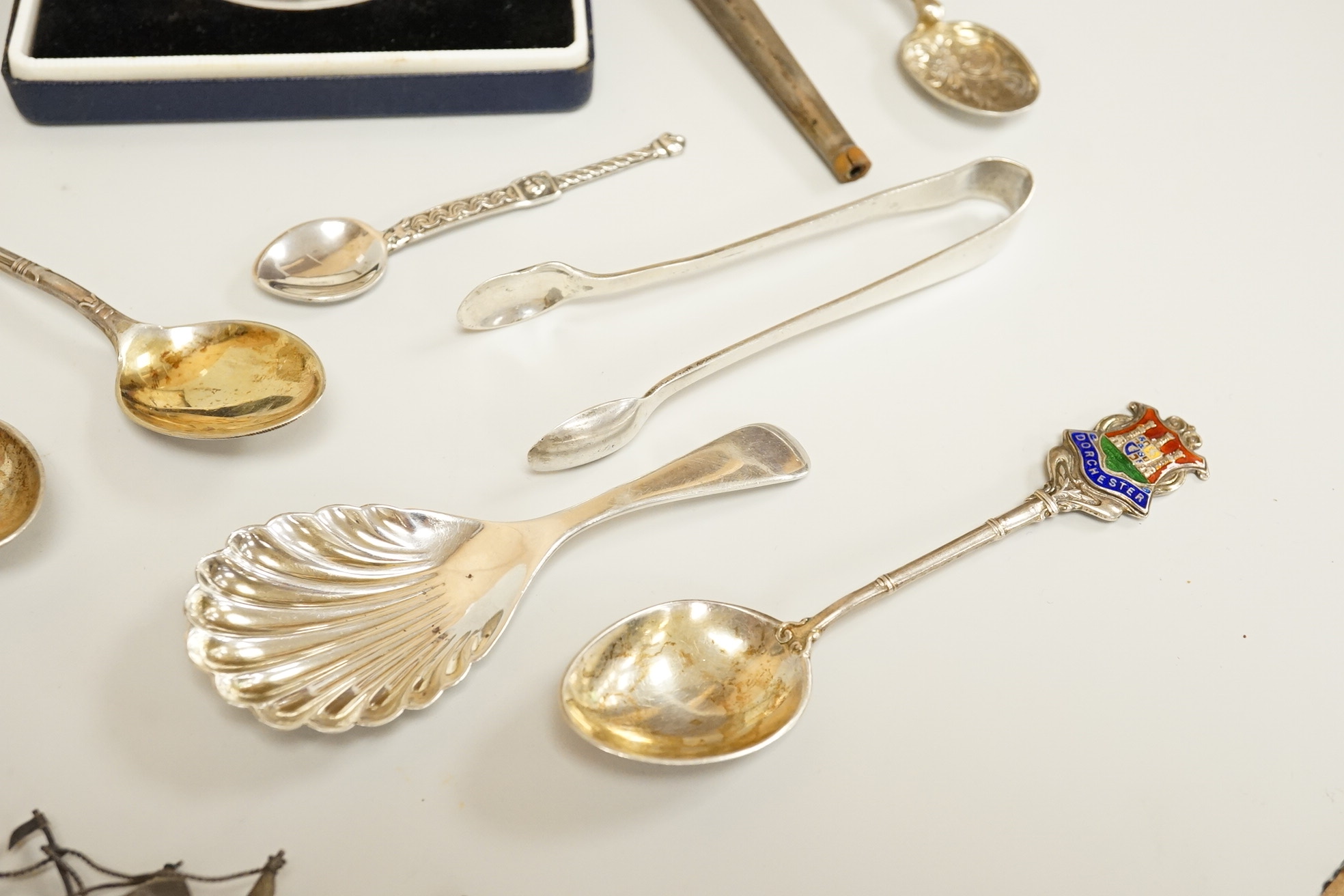 Assorted small silver including a mounted ribbed glass match strike, height 40mm, a small Scottish sterling spoon by Hamish Dawson Bowman, 76mm, a pair of George IV silver sugar tongs, commemorative spoons, an early 20th